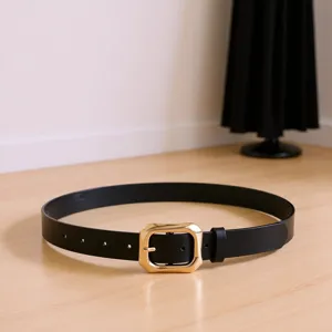 Einfacher vielseitiger schwarzer Damen-Gürtel mit eleganter goldener Schnalle auf Holz