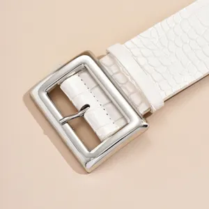 Close-up detail of a stylish white crocodile pattern belt with large silver buckle.