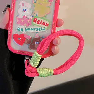 Détail de la dragonne de téléphone tissée rose vif avec accents vert contrastés