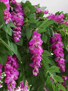 Detailed view of artificial pink wisteria blossoms and green leaves for decoration