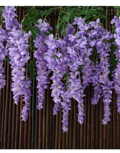 Detailed view of realistic artificial purple wisteria flowers hanging against a bamboo wall.