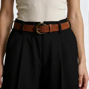 Detailed view of the brown suede belt with a vintage antique brass round pin buckle.