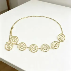 Close-up detail of stylish gold metal waist chain with elegant spiral circles for women.