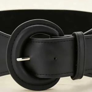 Detail view of a black wide waist belt featuring a large round buckle mechanism.