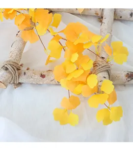 Dettaglio ravvicinato di foglie di ginkgo artificiali su rami decorativi di betulla.