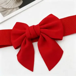 Close-up detail of a vibrant red elastic waist belt featuring a large decorative bow
