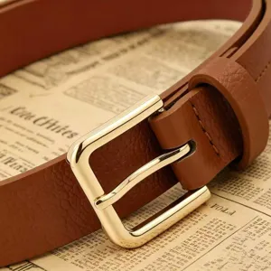 Gros plan détaillé de la boucle carrée dorée sur une ceinture en similicuir marron grainé