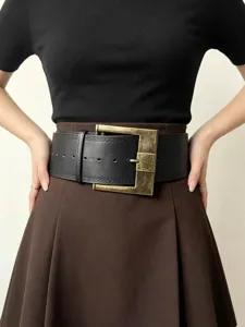 Dettaglio cintura in pelle larga, primo piano sulla elegante fibbia quadrata in metallo anticato.
