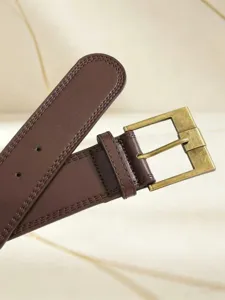 Primo piano dettagliato di cintura in pelle marrone vintage con fibbia quadrata.