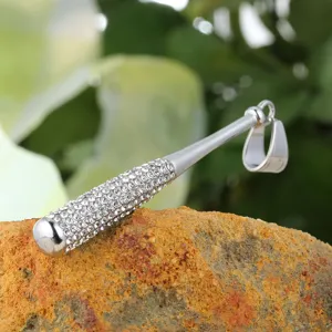 Detail view of an iced out baseball bat pendant in titanium steel on a rock.