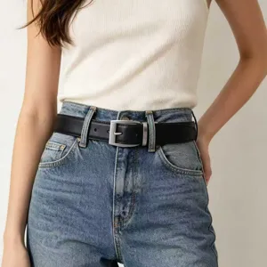 Detailed view of a classic black leather belt with a silver needle buckle on blue denim jeans