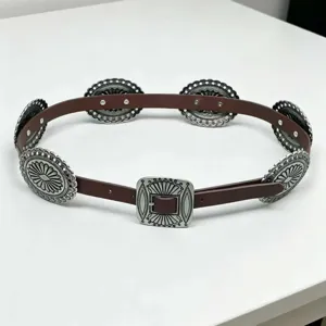 Detailed view of a Western vintage leather belt with ornate silver carved concho plates