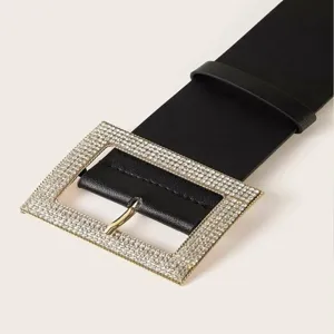 Ancho cinturón negro de cuero con hebilla rectangular de pedrería, accesorio de moda.