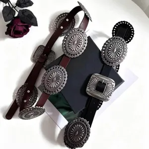 Close-up of vintage Western leather belts with carved silver-tone metal medallions
