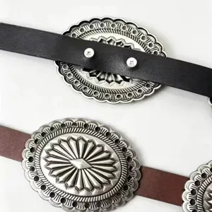 Close-up of vintage Western carved silver metal buckles on black and brown leather belts.