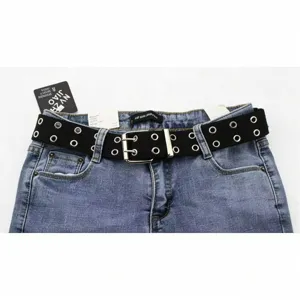Vue détaillée d'une ceinture en toile noire avec double œillets argentés sur un jean bleu
