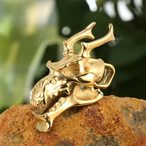 Detailaufnahme eines goldenen Drachenschädel-Anhängers aus Edelstahl auf einem Stein