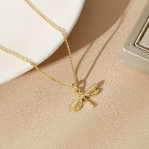 Detailed macro view of a gold-plated dragonfly pendant on a box chain necklace