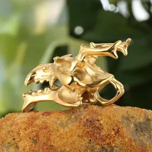 Detailansicht eines goldenen Tierschädel-Anhängers im Punk-Stil auf rauem Steinboden