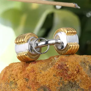 Detailed macro view of a gold and silver stainless steel dumbbell pendant on a rock
