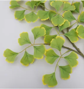 ramo di foglie di ginkgo artificiale in dettaglio, pianta finta verde gialla decorazione autunnale.