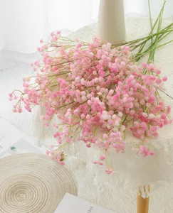 Close-up of pink artificial baby's breath flowers arranged nicely on a white lace tablecloth.