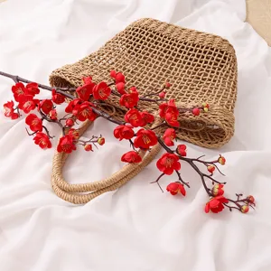 Realistic artificial red plum blossom branch on straw bag for home decor or floral arrangement