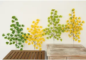 Dettaglio di ramo di ginkgo artificiale, decorazione di pianta finta verde e gialla.