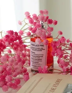Elegant perfume bottle surrounded by pink gypsophila flowers, delicate fragrance product detail.