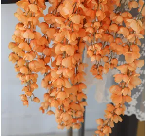 Close-up of vibrant orange artificial hanging silk wisteria vines for wedding decor
