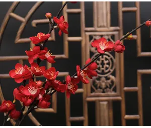 Artificial red plum blossom branch fake flower for home indoor decor, close up detail.