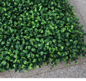 Closeup detail view of artificial Milan grass turf wall panel, dense green leaves texture.