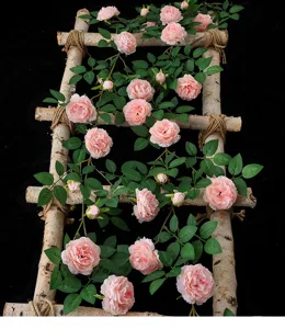 Detailansicht einer rosa künstlichen Pfingstrosenrebe an einer Birkenholzleiter