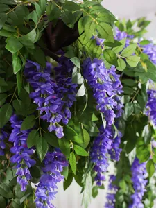 Close-up detail of realistic purple artificial wisteria hanging flowers and leaves.