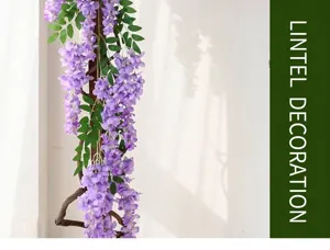 Detailed view of artificial purple wisteria vines hanging against a white wall with shadows.