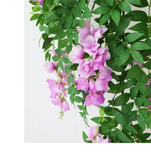 Dettaglio ravvicinato di fiori di vite pendenti rosa artificiali con foglie verdi rigogliose