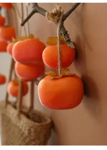 Detailansicht naturgetreuer künstlicher Orangen-Persimonen an einer natürlichen Hanfschnur.