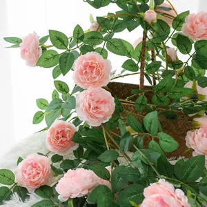 Künstliche rosa Pfingstrosenranken mit realistischen Blättern in einem geflochtenen Korb.