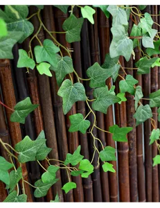 Close-up detail of artificial ivy vines climbing a dark bamboo fence decoration
