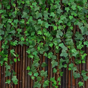 Realistic artificial ivy vines hanging against a dark brown bamboo fence backdrop