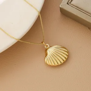 Detailed macro view of a glossy gold-plated shell pendant on a delicate box chain.