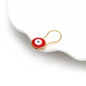 Primo piano dettagliato di una spilla turca Evil Eye rossa su piatto di ceramica bianca.