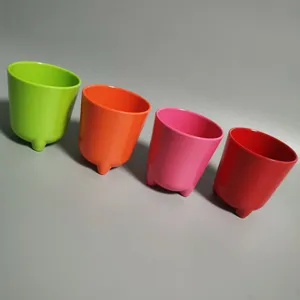 Detail view of colorful melamine children water cups with cute feet base in four bright hues.