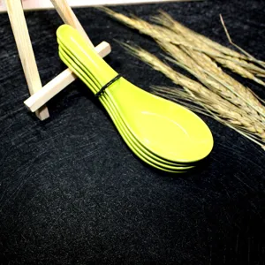Detailed view of vibrant green melamine soup spoons stacked on a black textured background.