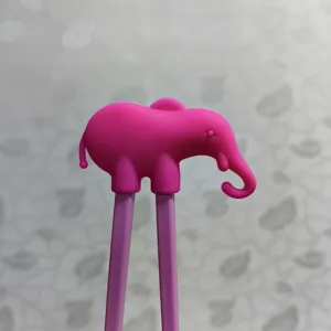 Pink elephant silicone head detail on kids training chopsticks, cute design for baby utensils.