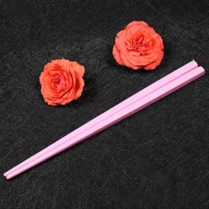 Close-up of pink melamine candy-colored 18cm children's chopsticks on a dark surface