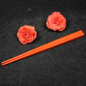 Close-up view of bright orange melamine children's chopsticks on a dark textured background