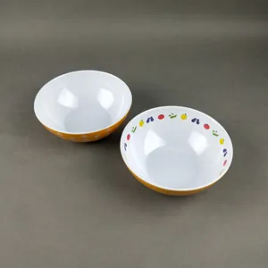 Melamine salad bowl detail showcasing vibrant orange color with white polka dots and fruit patterns.