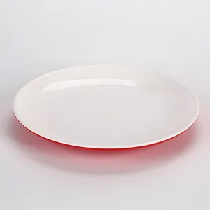 Gros plan d'une assiette ronde en mélamine blanche avec une base rouge