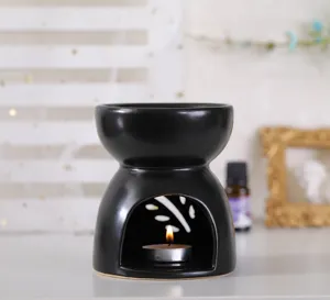 Primer plano del quemador de cera de cerámica negro mate con recortes de hojas